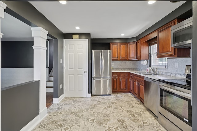 kitchen featuring decorative backsplash, stainless steel appliances, sink, and ornate columns