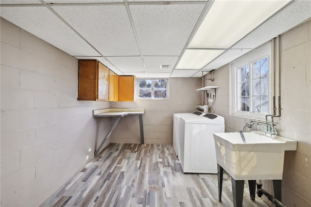 laundry room with cabinets, light hardwood / wood-style flooring, sink, and separate washer and dryer