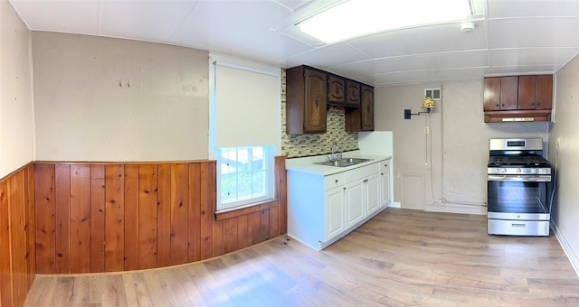 kitchen featuring sink, light hardwood / wood-style floors, stainless steel gas range, and backsplash