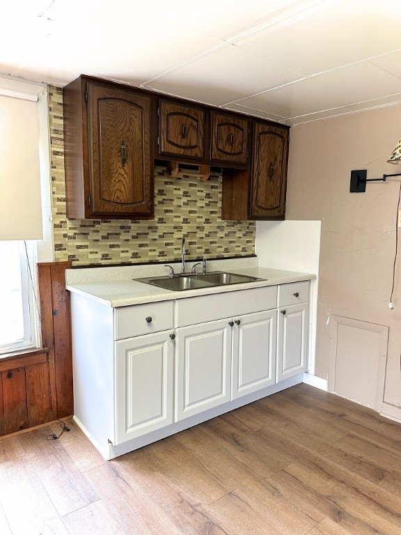 kitchen featuring dark brown cabinetry, sink, light hardwood / wood-style flooring, and decorative backsplash