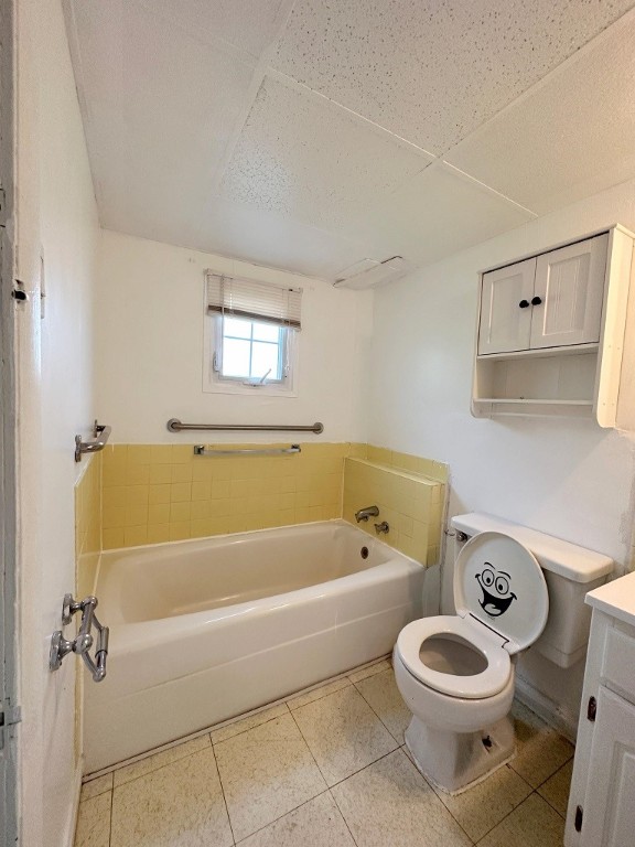 bathroom featuring vanity, toilet, tile patterned flooring, and a washtub