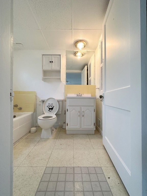 bathroom featuring vanity, toilet, a drop ceiling, and a bath