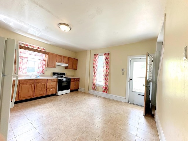 kitchen featuring white range with gas stovetop, sink, and light tile patterned floors