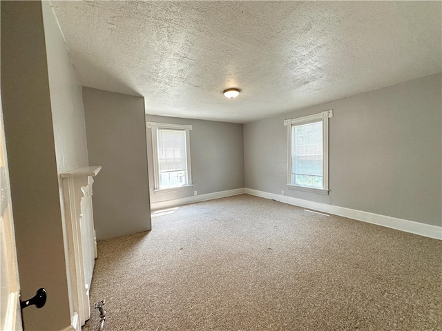 unfurnished living room featuring a healthy amount of sunlight, carpet flooring, and a textured ceiling