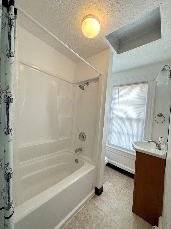 full bathroom featuring a textured ceiling, toilet, shower / bath combo with shower curtain, vanity, and tile patterned flooring