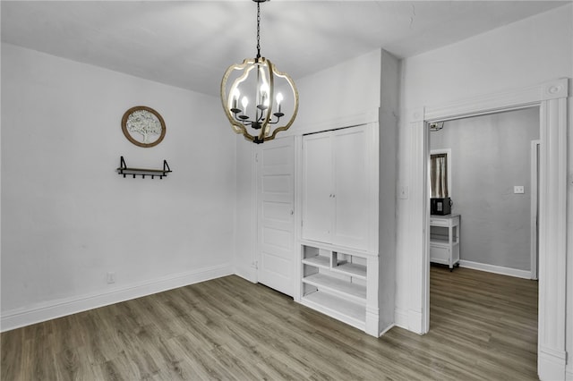 unfurnished dining area with wood-type flooring and an inviting chandelier