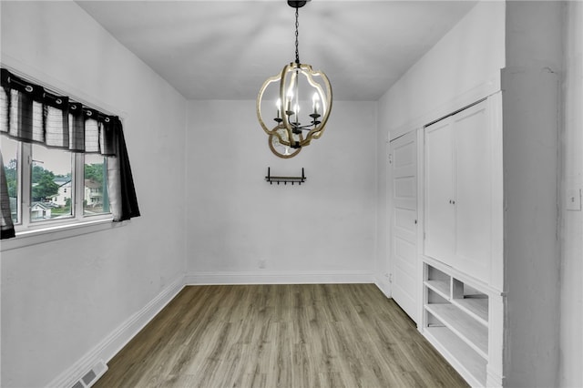 unfurnished dining area with a notable chandelier and hardwood / wood-style flooring