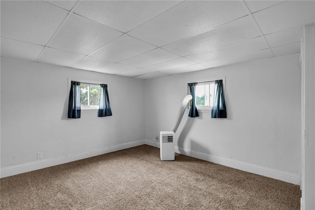 unfurnished room with a drop ceiling, a healthy amount of sunlight, and carpet flooring