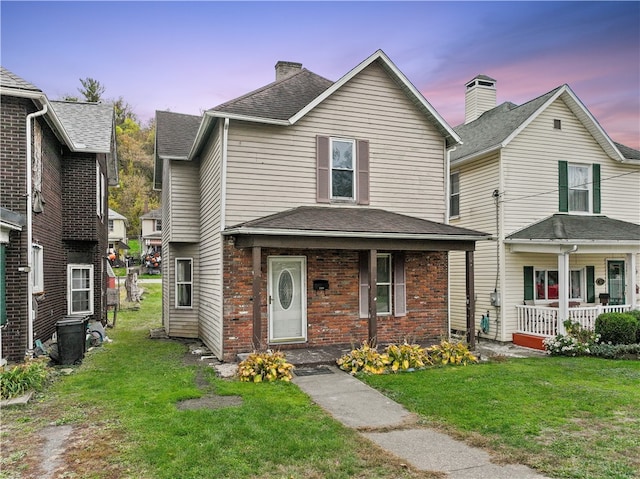 view of property with covered porch and a lawn