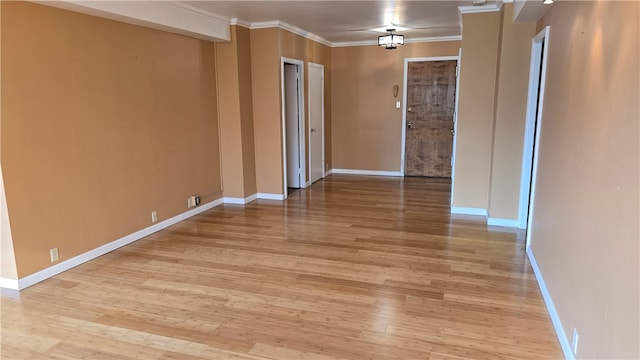 unfurnished room with ornamental molding, light hardwood / wood-style flooring, and an inviting chandelier