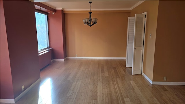 unfurnished dining area with light hardwood / wood-style floors, ornamental molding, and a chandelier