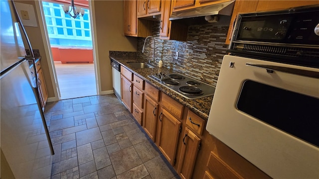 kitchen with backsplash, dark stone counters, sink, a notable chandelier, and appliances with stainless steel finishes