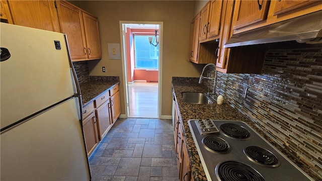 kitchen with backsplash, sink, stainless steel cooktop, and white refrigerator