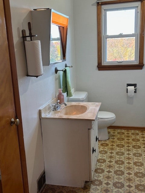 bathroom featuring a healthy amount of sunlight, vanity, and toilet