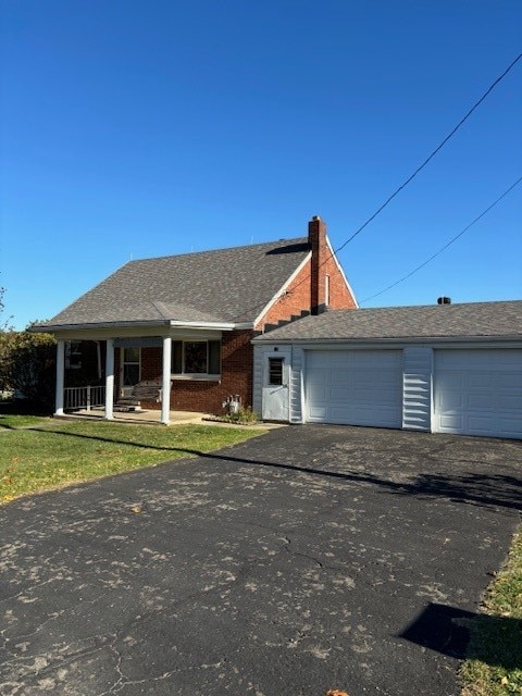 single story home with a porch, a front yard, and a garage