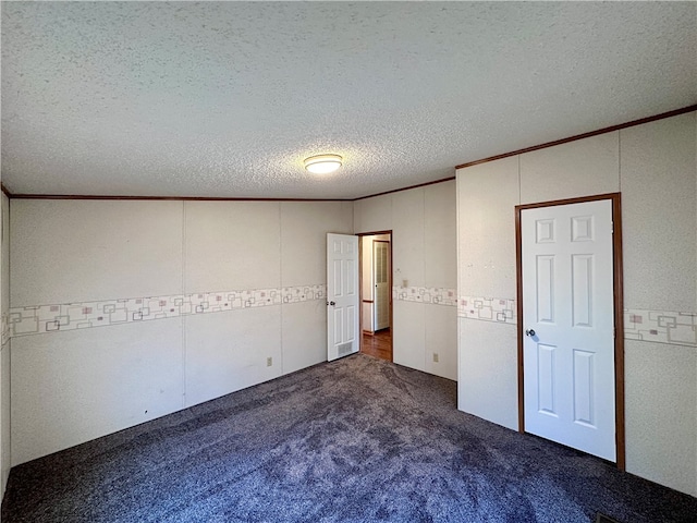 unfurnished bedroom with ornamental molding, dark colored carpet, and a textured ceiling