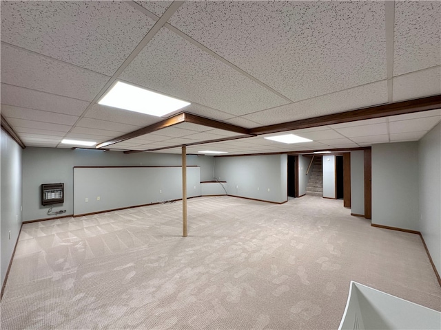 basement with light carpet, heating unit, and a paneled ceiling