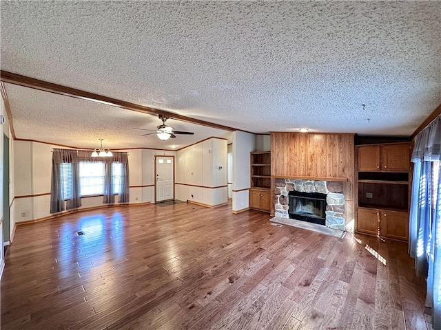 unfurnished living room featuring a stone fireplace, crown molding, a textured ceiling, and wood-type flooring