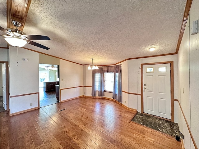 entryway with ceiling fan with notable chandelier, a textured ceiling, hardwood / wood-style floors, lofted ceiling, and ornamental molding