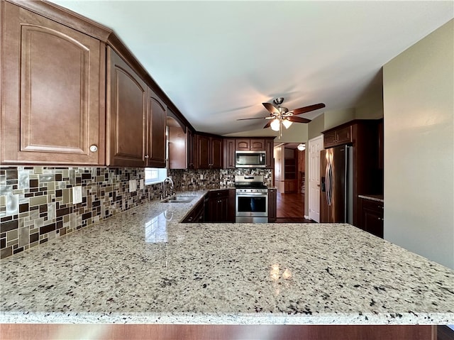 kitchen with light stone countertops, sink, appliances with stainless steel finishes, and kitchen peninsula