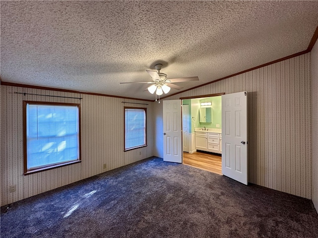 unfurnished bedroom featuring carpet, ceiling fan, a textured ceiling, ensuite bathroom, and crown molding