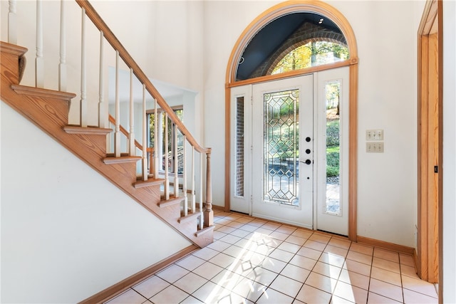 foyer with high vaulted ceiling and light tile patterned floors