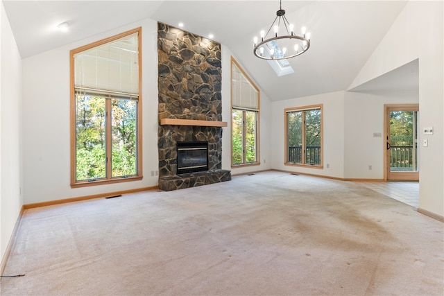 unfurnished living room featuring light carpet, lofted ceiling with skylight, a fireplace, and a wealth of natural light