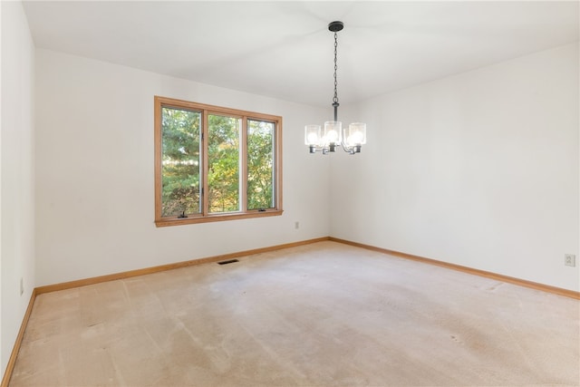 spare room featuring light carpet and a notable chandelier