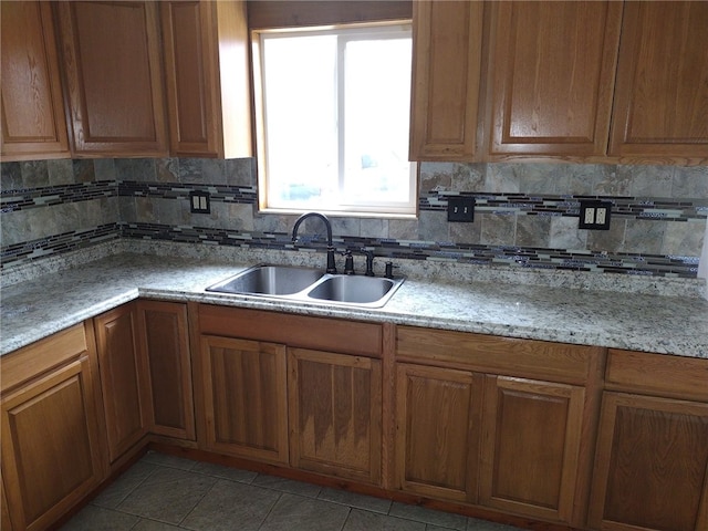 kitchen with light stone countertops, sink, decorative backsplash, and light tile patterned floors