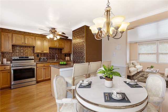 dining area with ceiling fan with notable chandelier, light hardwood / wood-style floors, sink, and crown molding