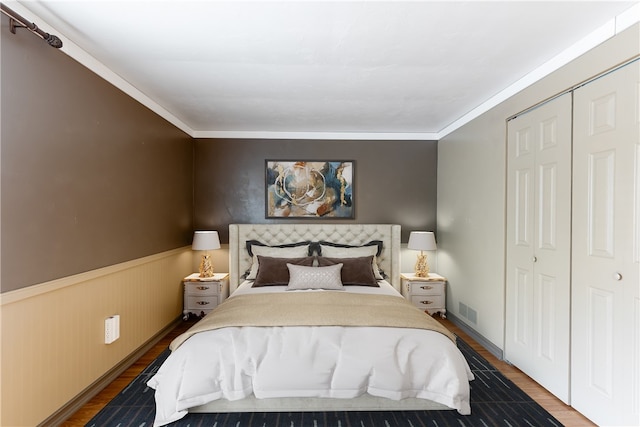 bedroom with hardwood / wood-style flooring, crown molding, and a closet