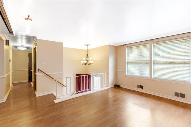 spare room featuring wood-type flooring and an inviting chandelier