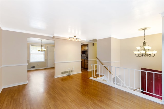 spare room featuring hardwood / wood-style flooring, an inviting chandelier, and crown molding