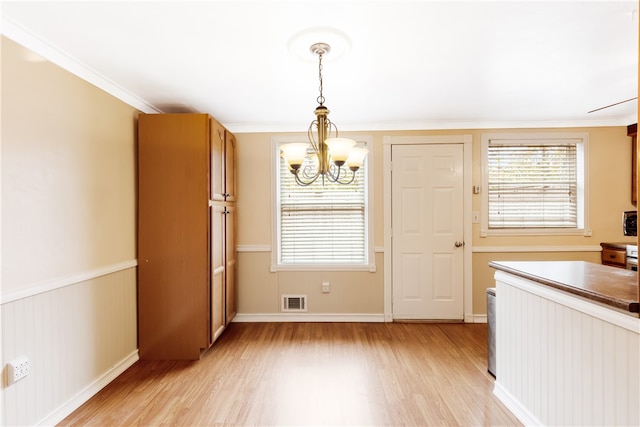 unfurnished dining area featuring an inviting chandelier, light hardwood / wood-style flooring, and ornamental molding