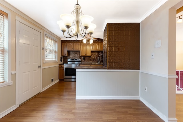 kitchen featuring hanging light fixtures, wood-type flooring, stainless steel electric range, and ornamental molding