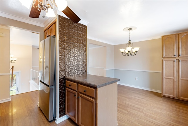 kitchen featuring ceiling fan with notable chandelier, light hardwood / wood-style floors, crown molding, pendant lighting, and stainless steel fridge