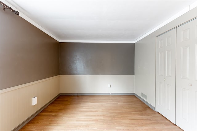 interior space featuring a closet, light wood-type flooring, and ornamental molding