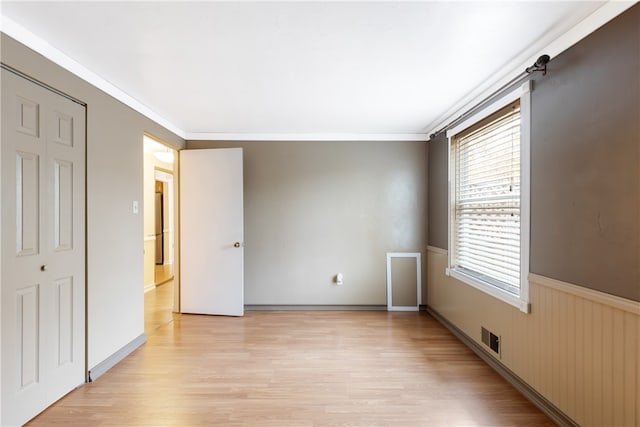 unfurnished bedroom with a closet, light hardwood / wood-style flooring, and crown molding