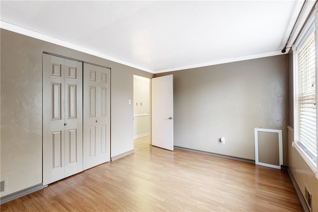 unfurnished bedroom featuring light hardwood / wood-style floors, multiple windows, and ornamental molding