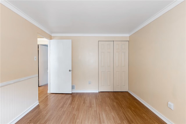 unfurnished bedroom with a closet, light hardwood / wood-style flooring, and crown molding