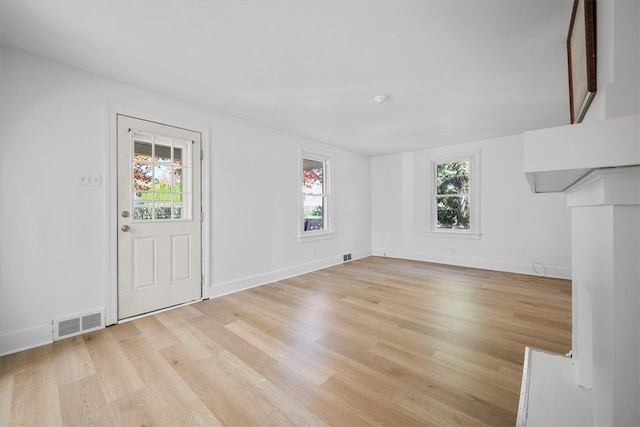 unfurnished living room featuring a wealth of natural light and light hardwood / wood-style flooring