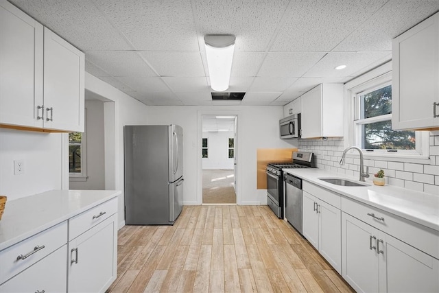 kitchen with white cabinetry, stainless steel appliances, sink, and light wood-type flooring