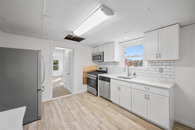 kitchen featuring appliances with stainless steel finishes, sink, light wood-type flooring, and white cabinets