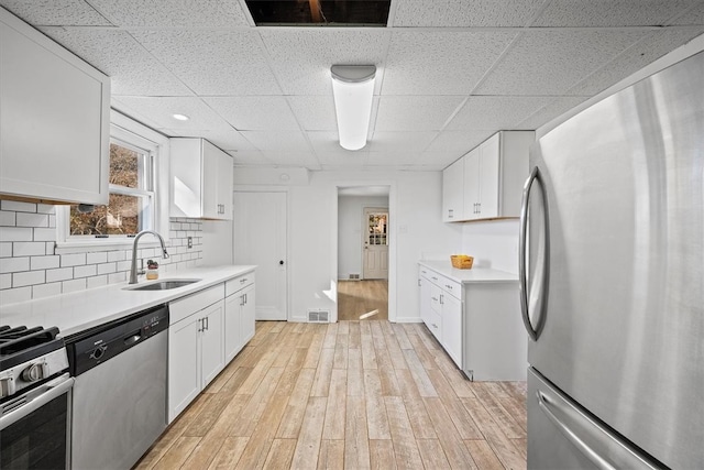 kitchen featuring decorative backsplash, light hardwood / wood-style flooring, stainless steel appliances, sink, and white cabinetry