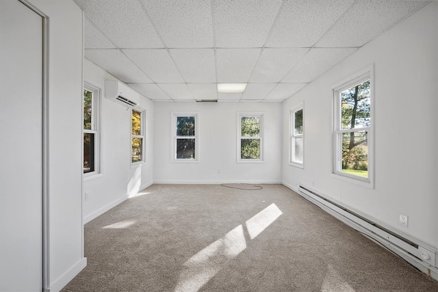 carpeted spare room featuring a wall mounted AC, a paneled ceiling, and baseboard heating