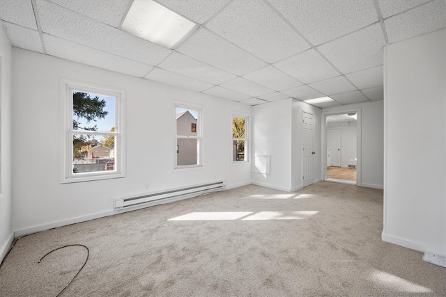 unfurnished room with light carpet, a drop ceiling, and a baseboard radiator