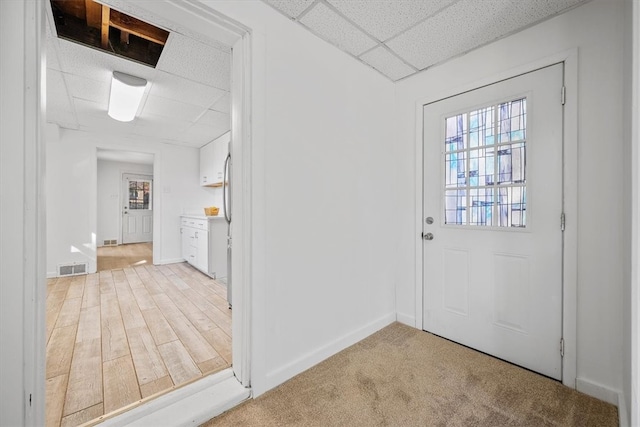 foyer entrance featuring a drop ceiling and light carpet