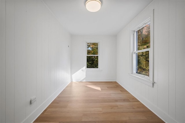 empty room featuring wooden walls and light hardwood / wood-style floors