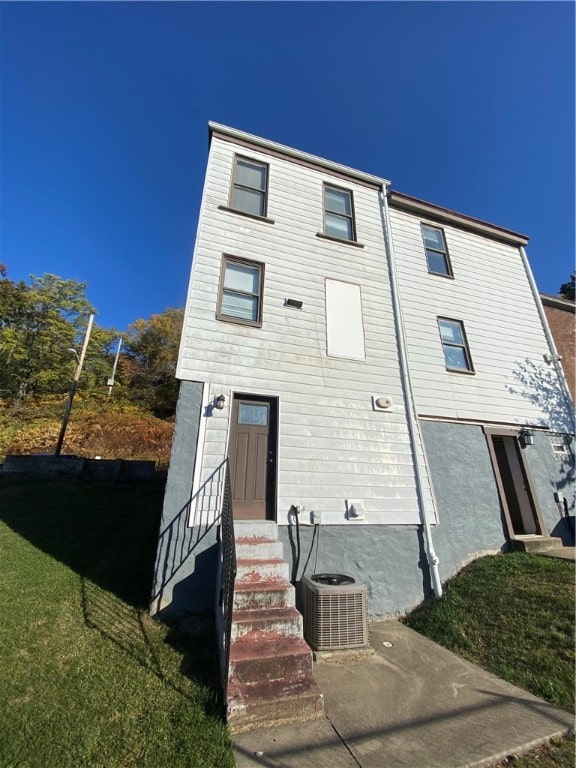 view of front of house with central AC and a front lawn