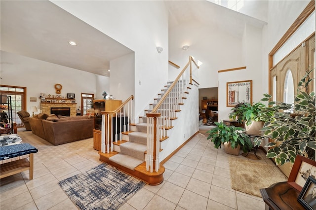 tiled entryway featuring a fireplace and a towering ceiling